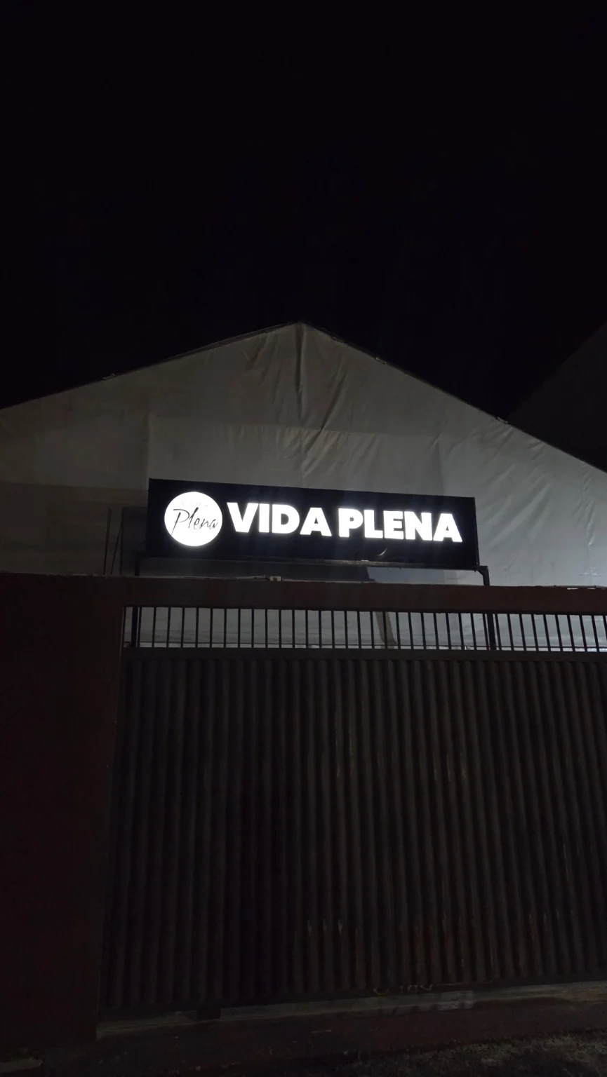 Letreiro luminoso da Vida Plena aceso na fachada durante a noite.
