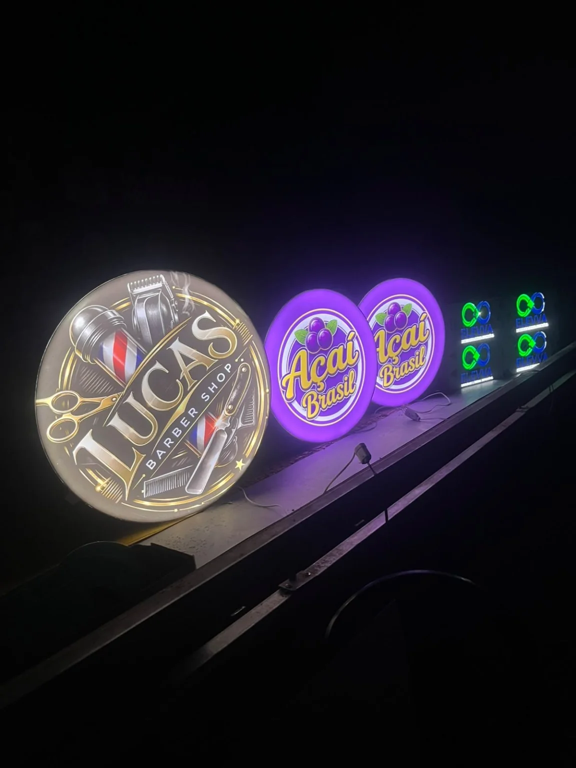 Luminosos de diferentes marcas acesos na bancada de produção.