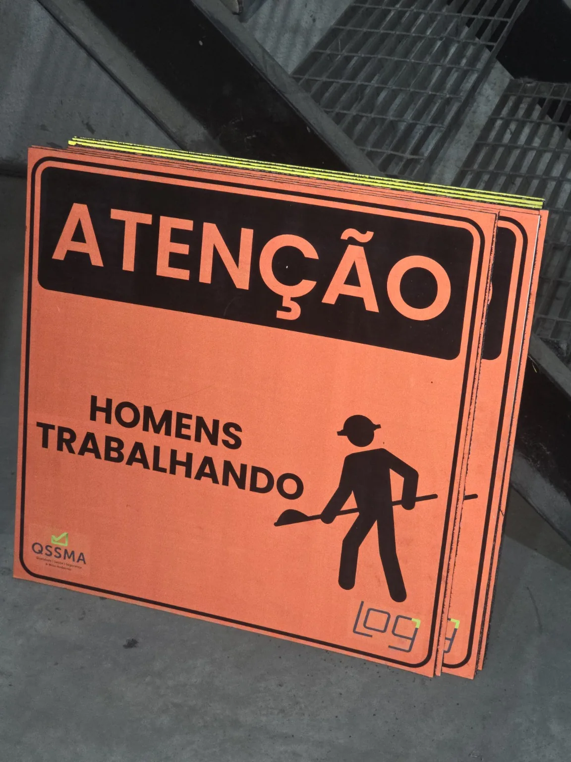 Placa laranja de atenção com identificação de homens trabalhando.
